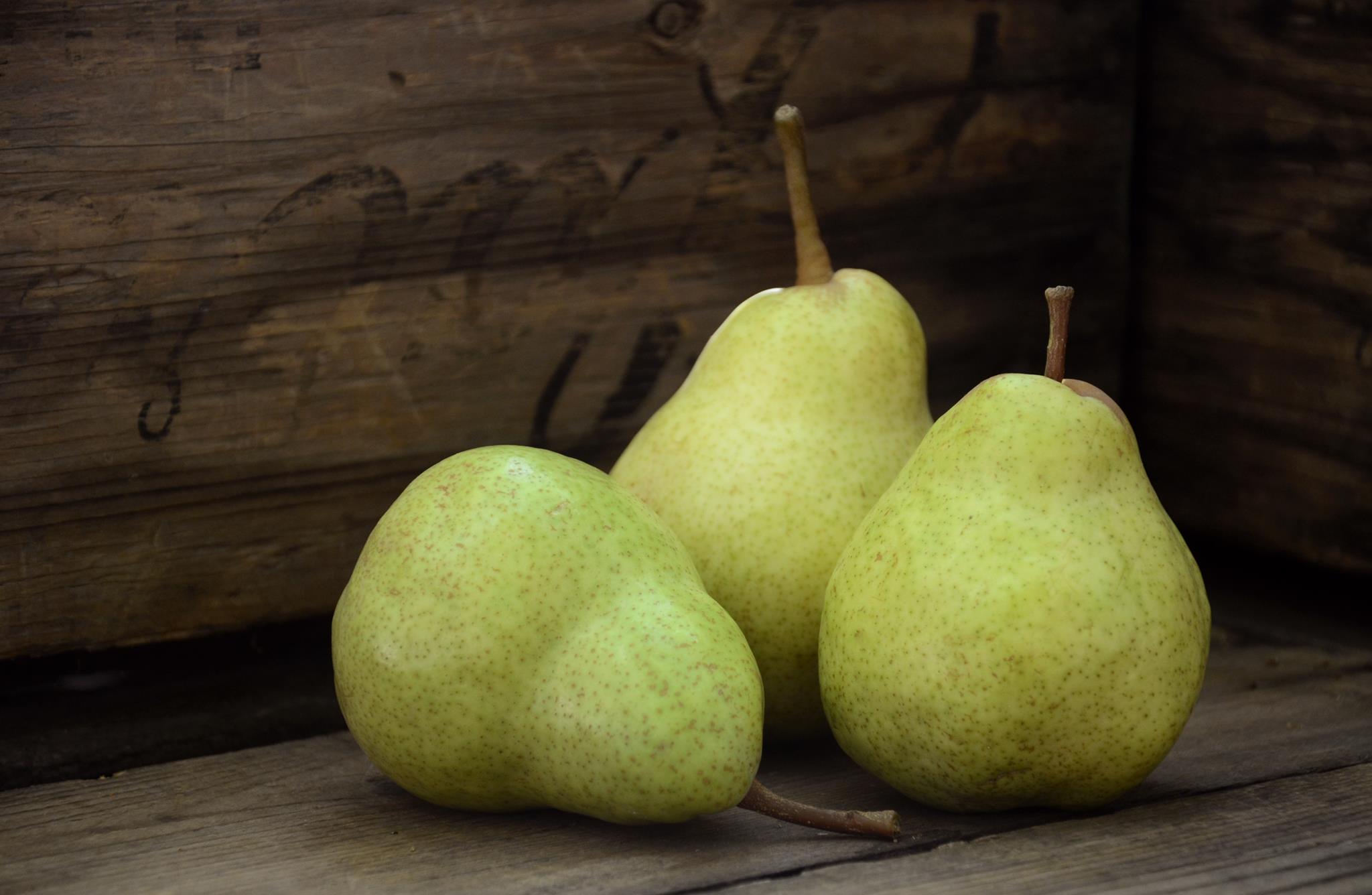 Three ripe pears resting on a weathered wooden fruit crate at Boorinakis Harper Ranch